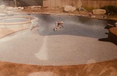 A worker spreads concrete at the bottom of an empty in-ground swimming pool under construction.